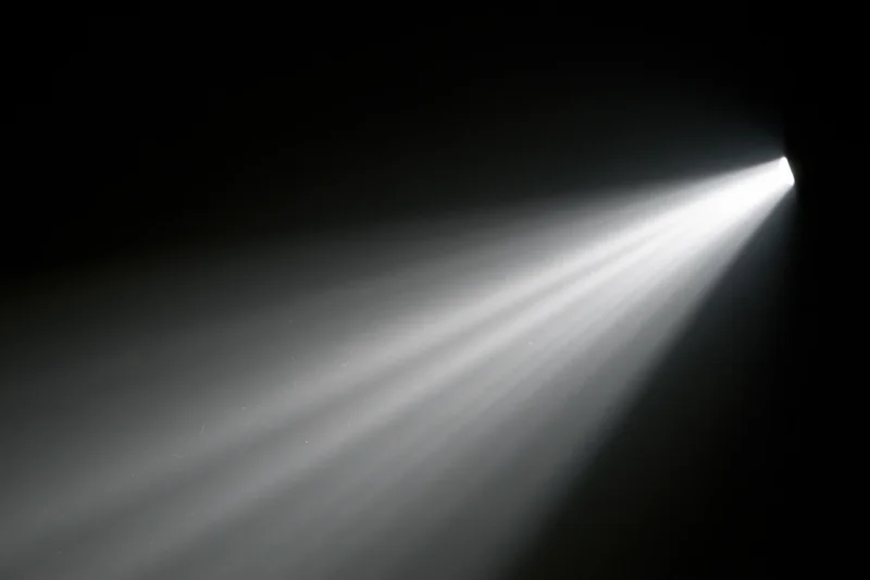 A projector beam cutting through a dark room with visible light rays and shadows