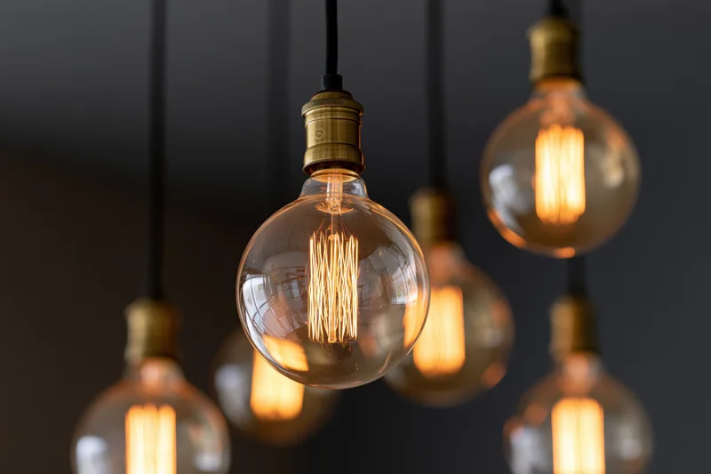 Vintage edison globe bulbs hanging in a cluster with warm glow against dark background