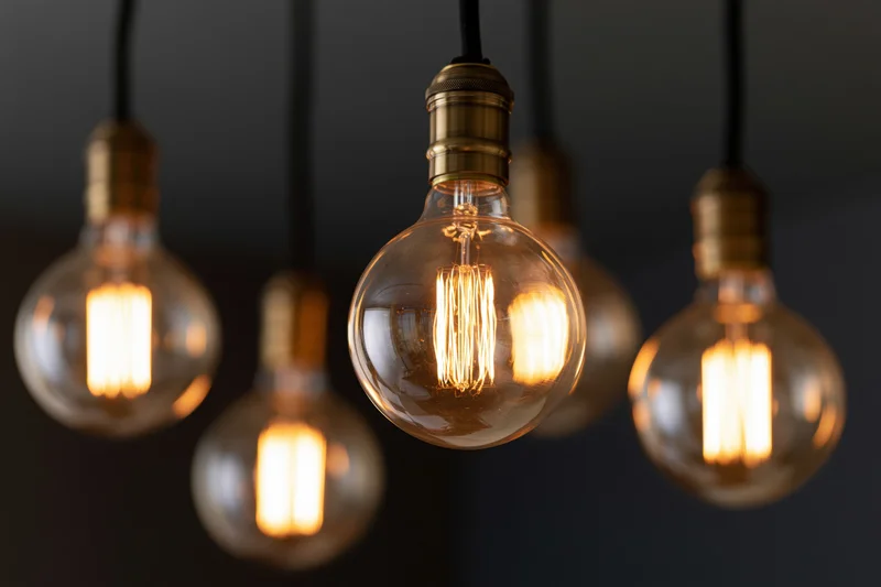 Vintage edison bulbs hanging in a cluster with warm glow against dark background