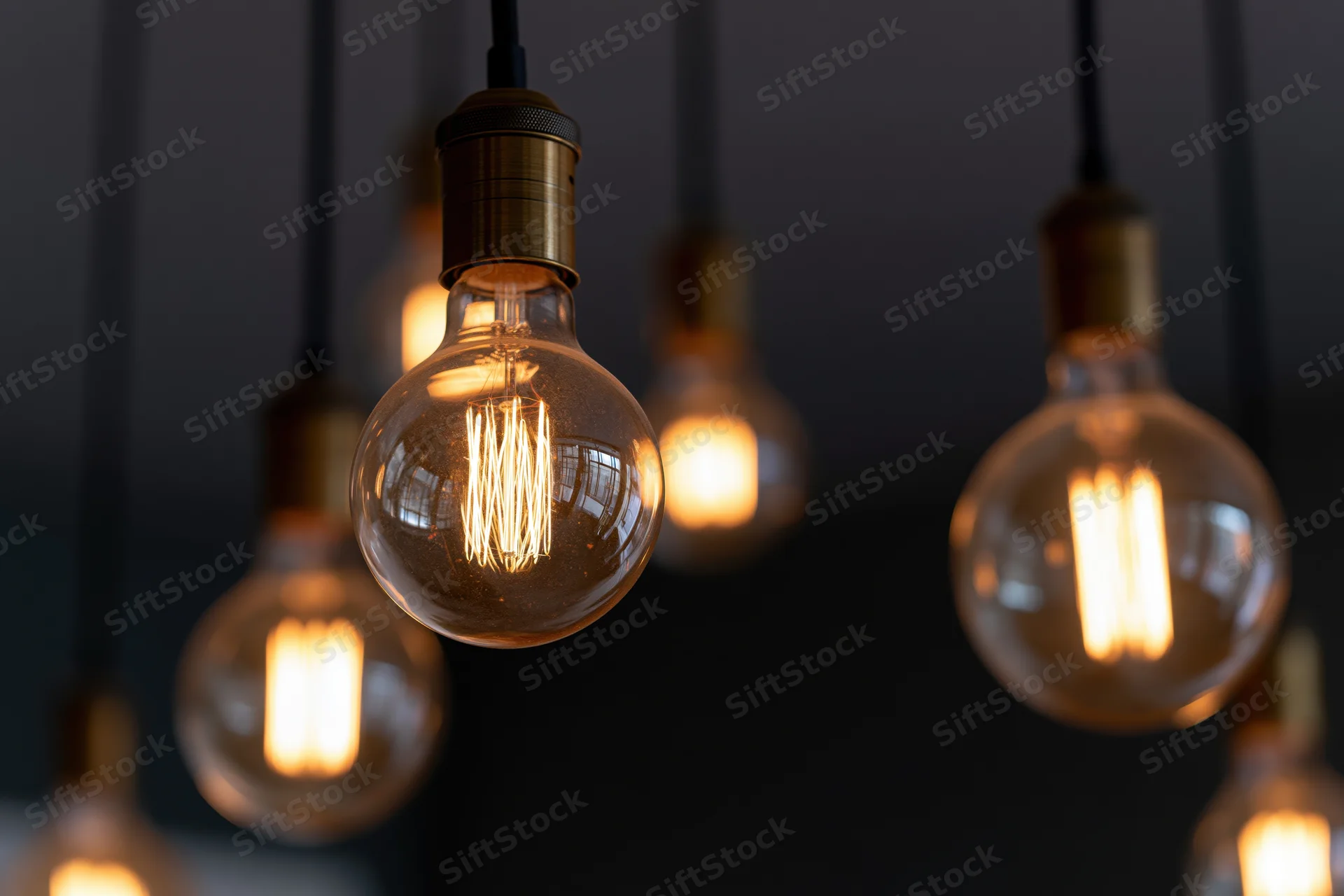Vintage edison bulbs hanging in a cluster with warm glow against dark background