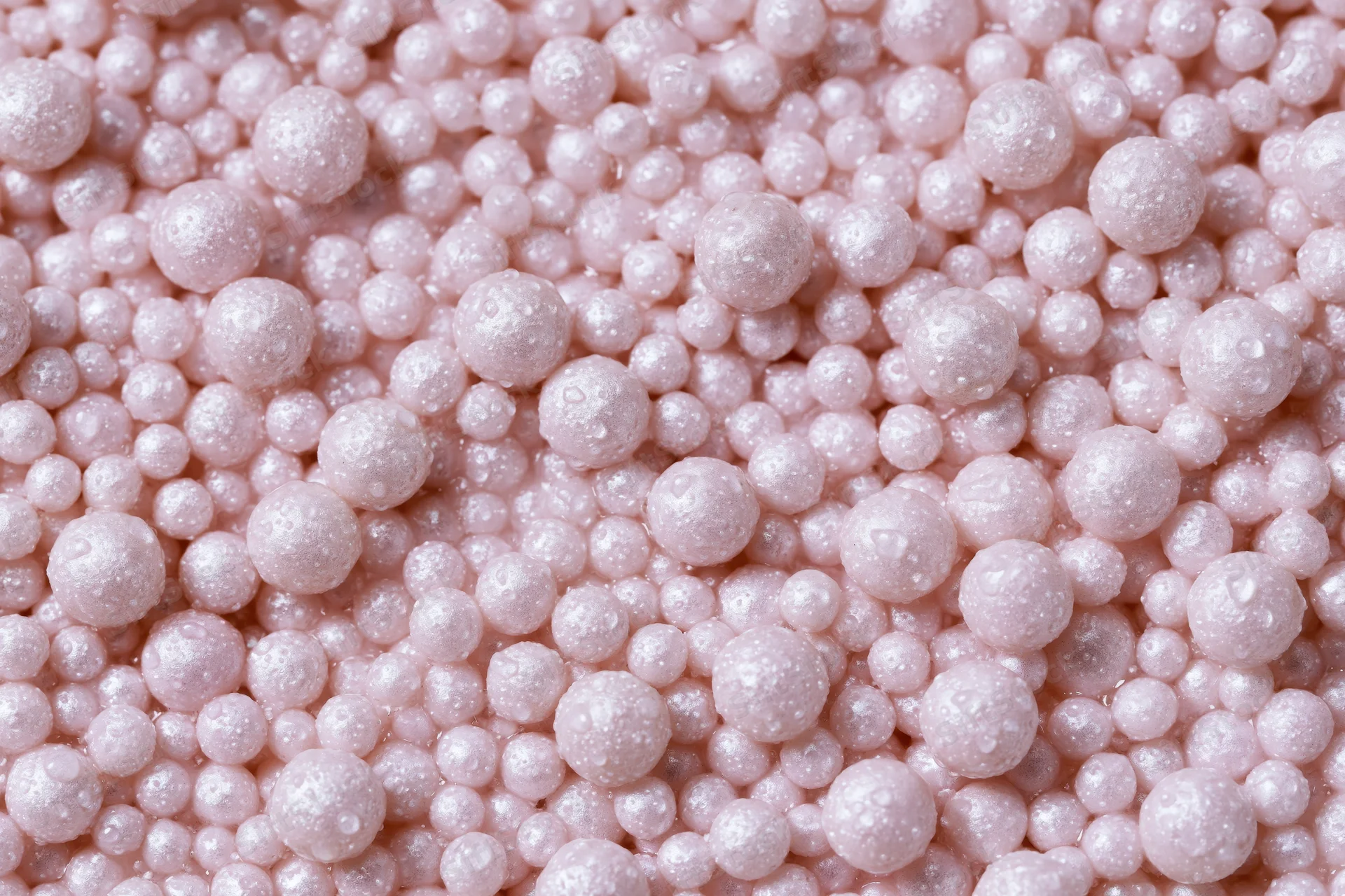 A pile of small pearlescent pink beads filling the frame