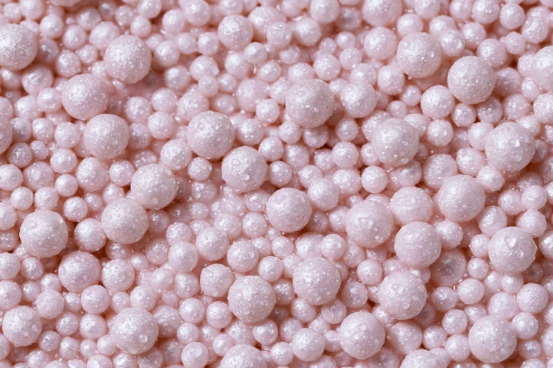 A pile of small pearlescent pink beads filling the frame