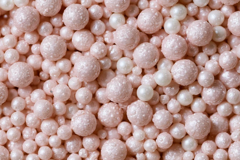 A pile of small pearlescent pink beads filling the frame