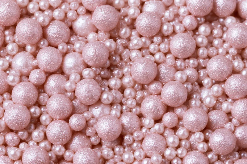 A pile of small pearlescent pink beads filling the frame