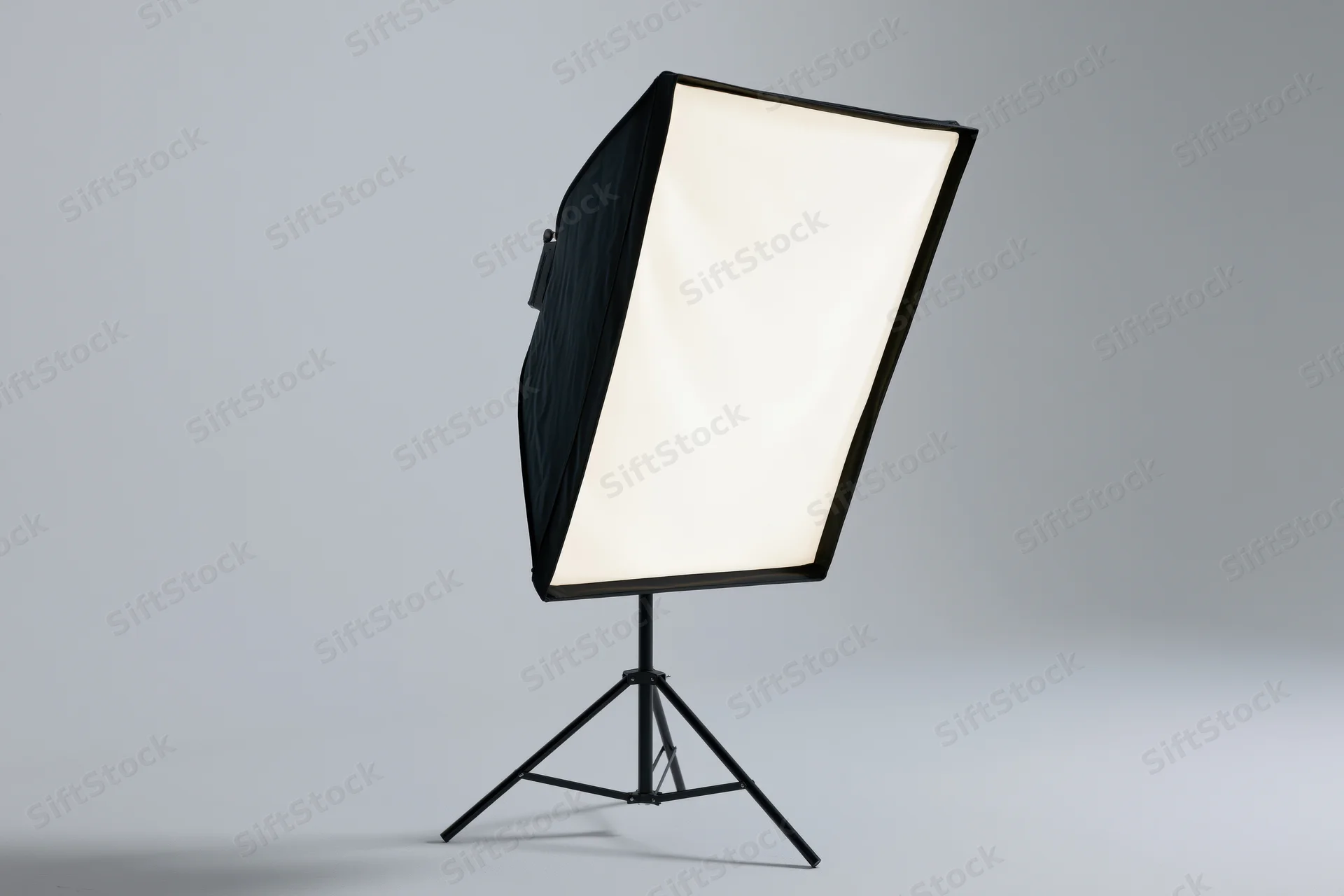 Rectangular softbox light on black metal tripod stand against plain gray background