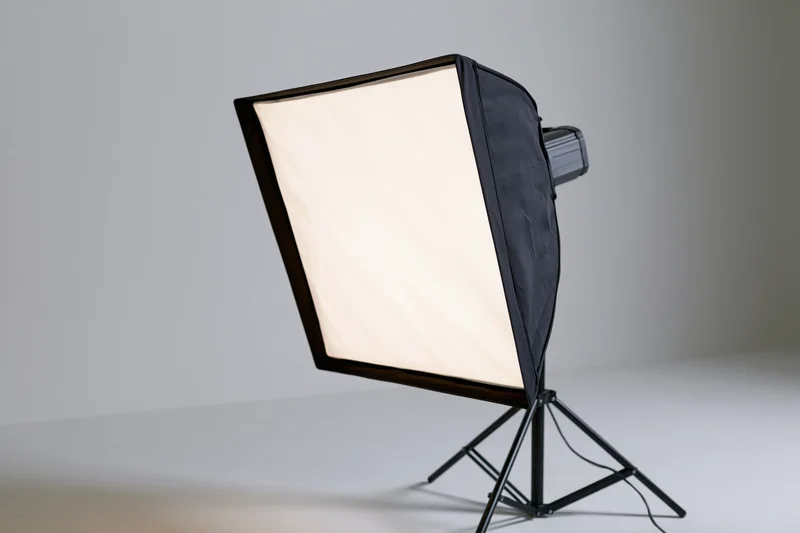 Softbox light mounted on black metal stand in studio setting with white background