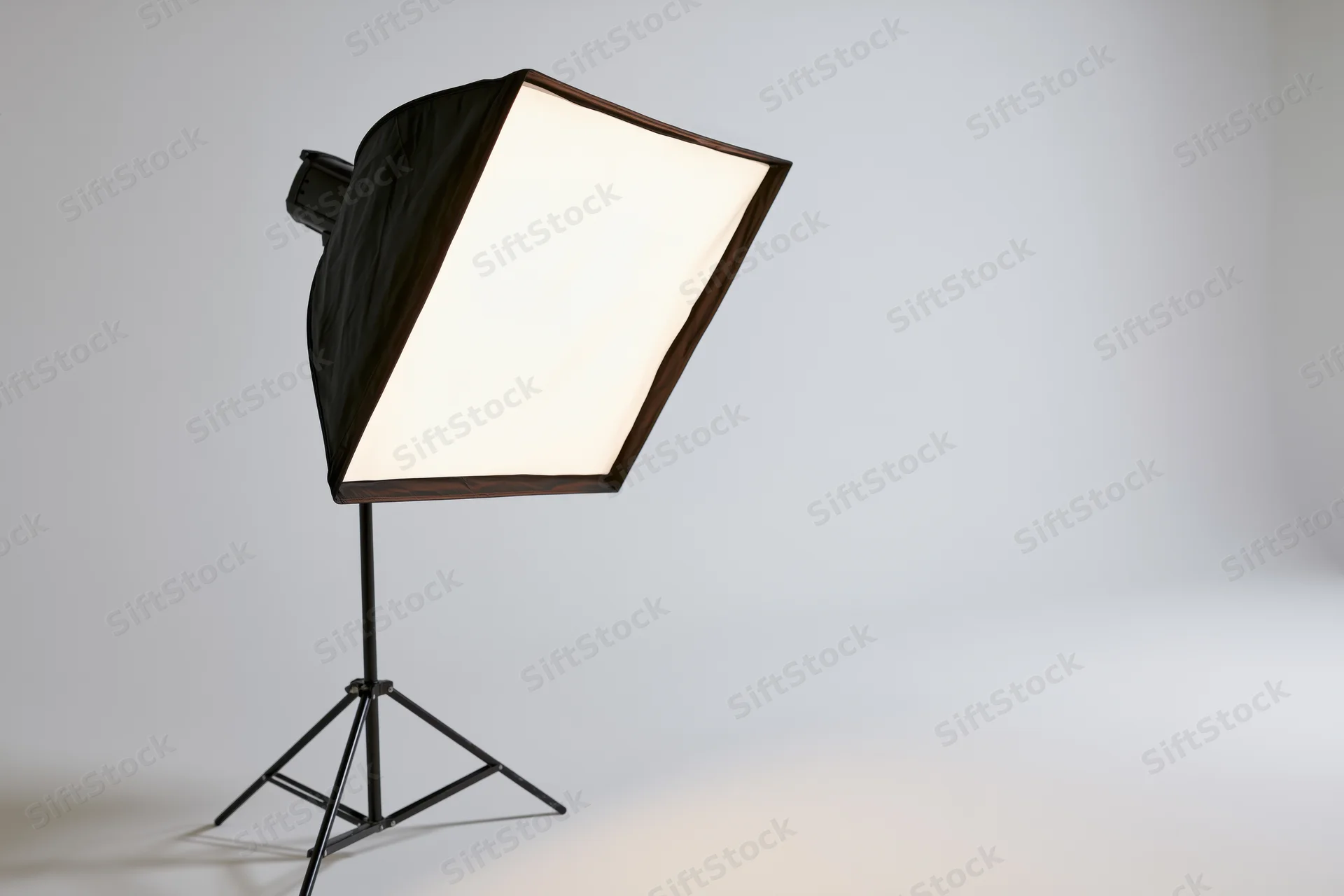 Softbox light on a black metal stand in a studio setting with white background
