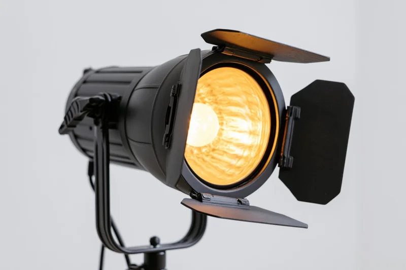 Professional studio strobe light with barn doors open on a stand, emitting warm glow