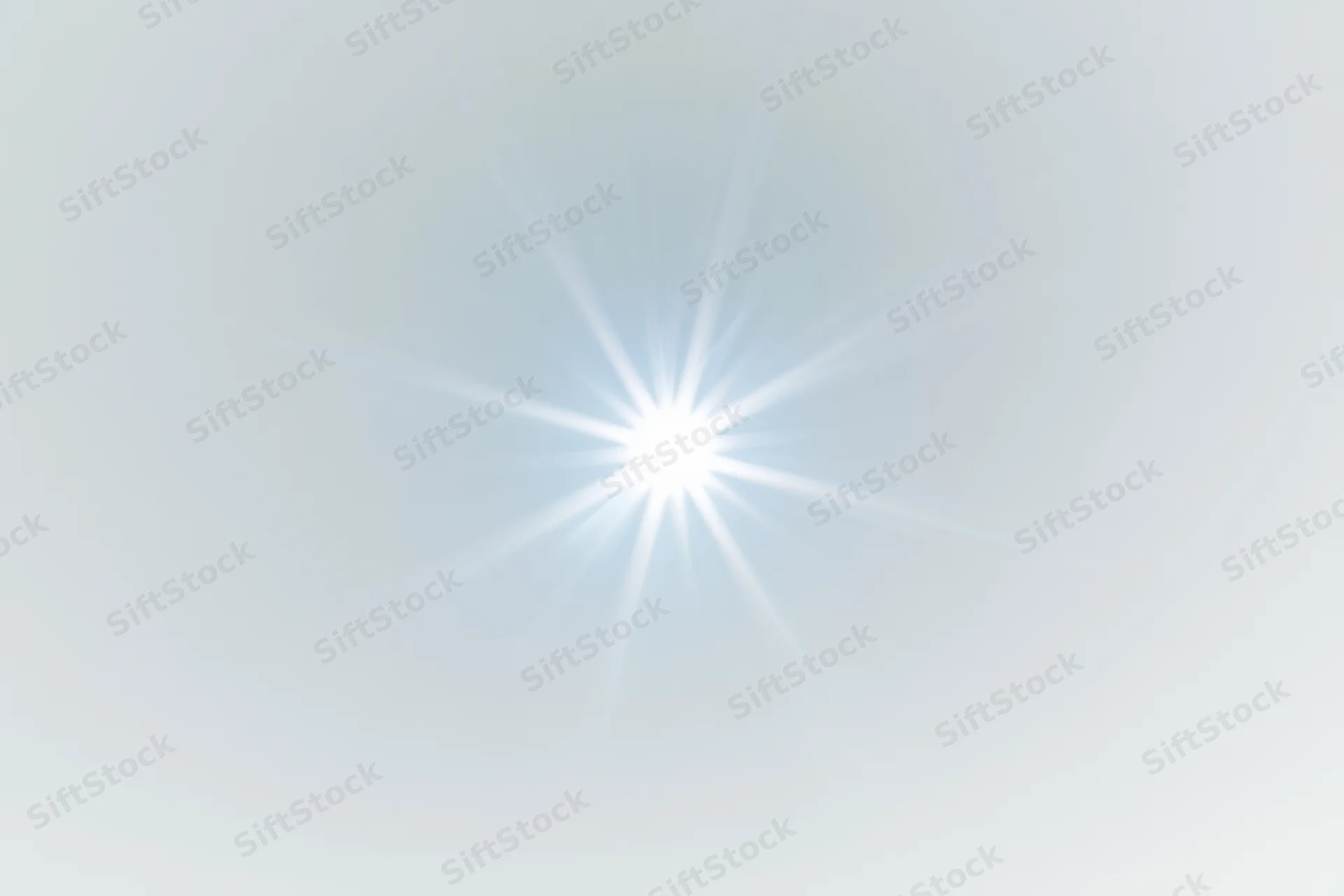 Bright lens flare starburst centered on a plain white background with soft gradient and copyspace