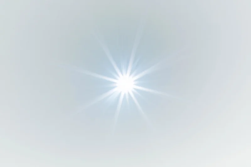 Bright lens flare starburst centered on a plain white background with soft gradient and copyspace