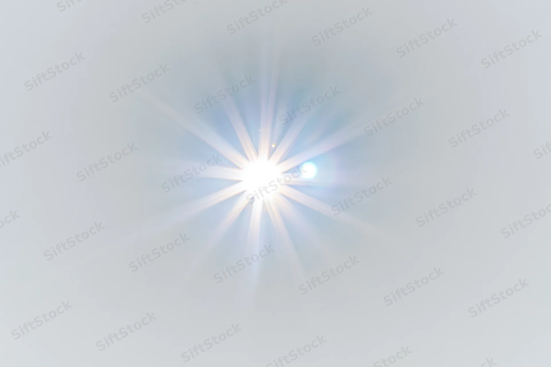 Bright lens flare starburst centered on plain white background