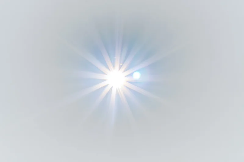Bright lens flare starburst centered on plain white background