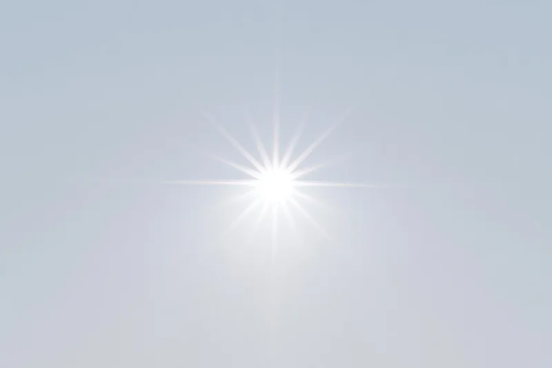 Bright lens flare starburst centered on a pure white background