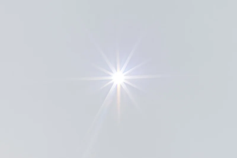Bright lens flare starburst centered on a pure white background