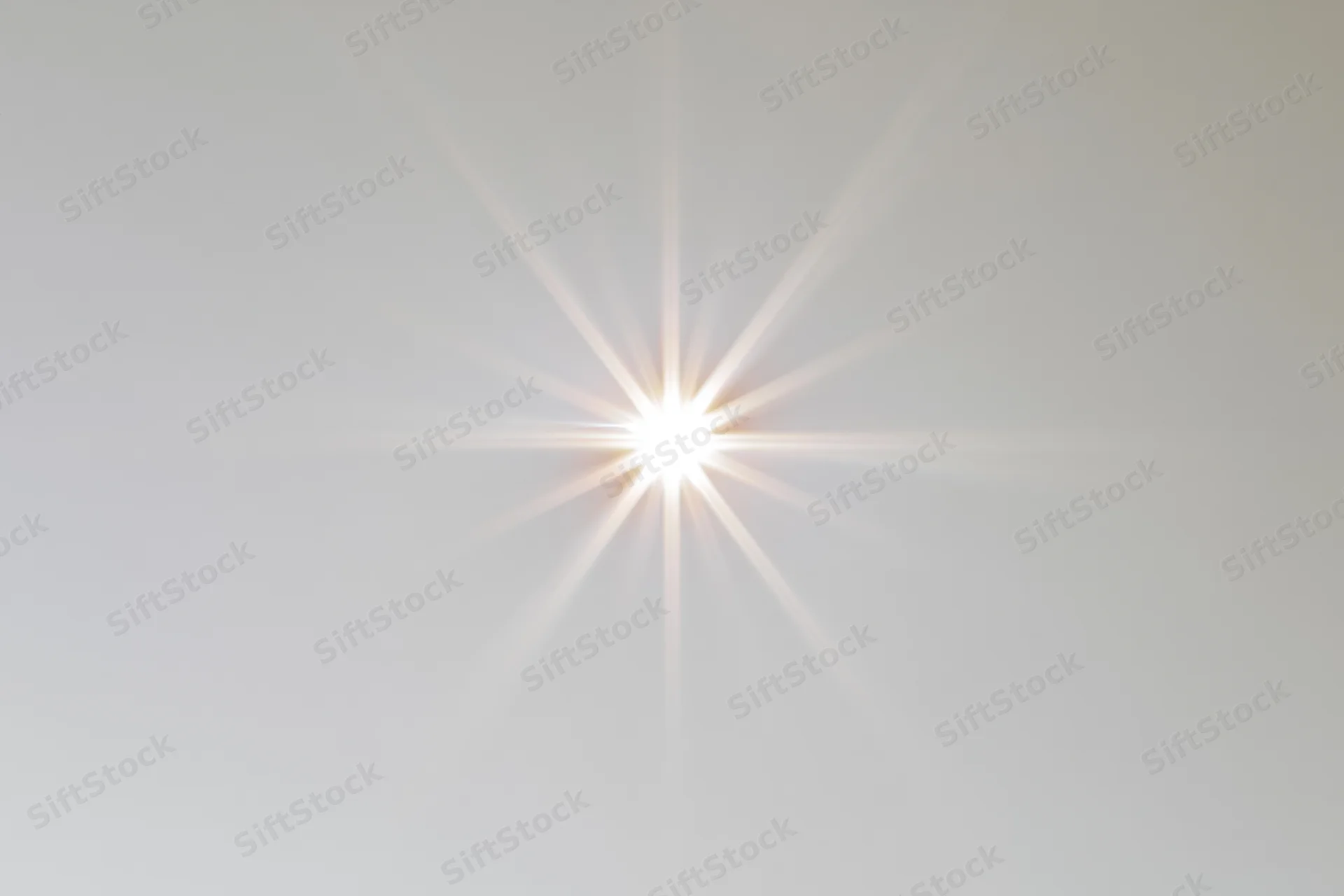 Bright lens flare starburst centered on a pure white background