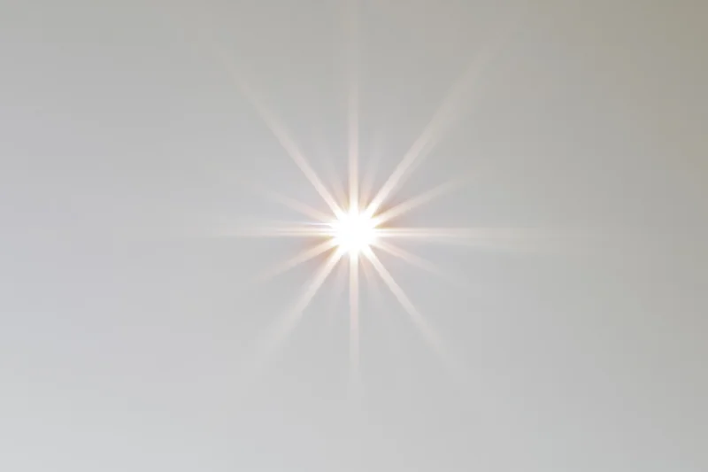 Bright lens flare starburst centered on a pure white background