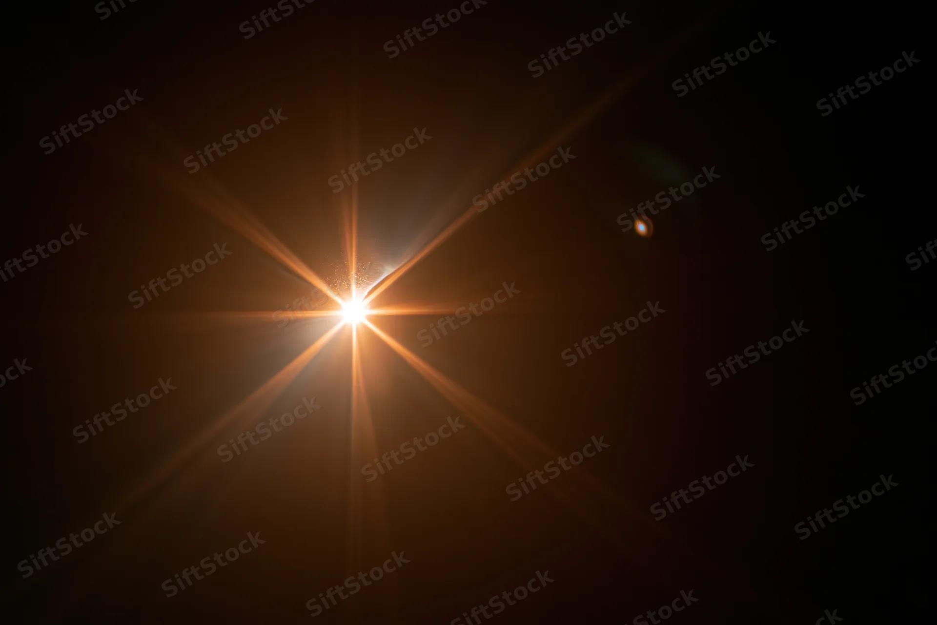 Bright point of light with starburst flare against dark background