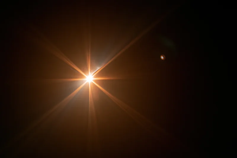 Bright point of light with starburst flare against dark background