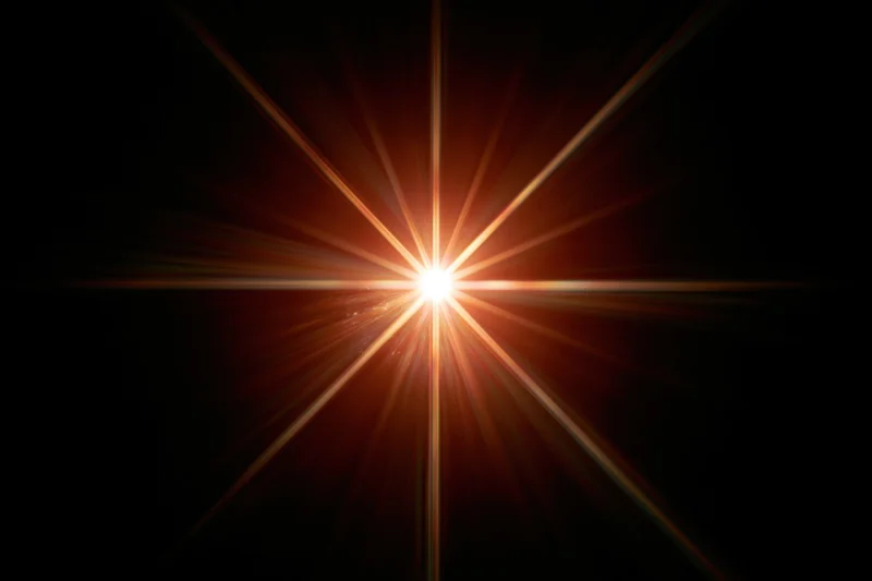 Bright point of light bursting with radial lens flare against dark background