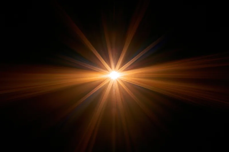 Bright point of light emitting radial lens flare against dark background