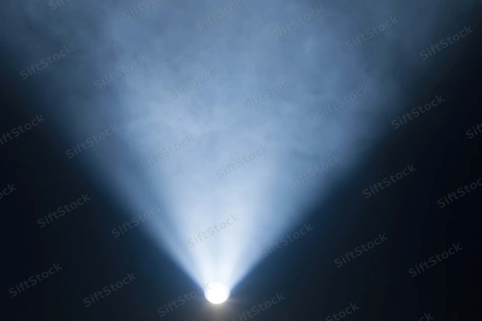 Bright white spotlight beam projecting upward into dark smoky air