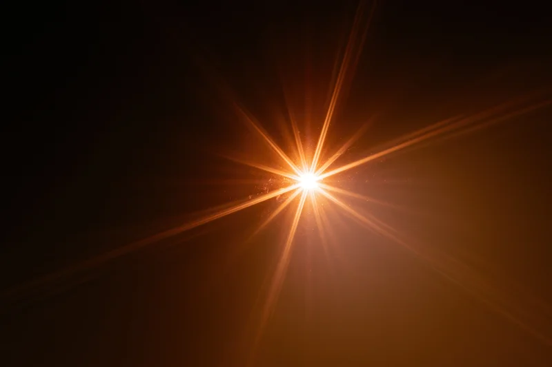 Intense light source bursting from center against dark background with radiant beams and warm glow