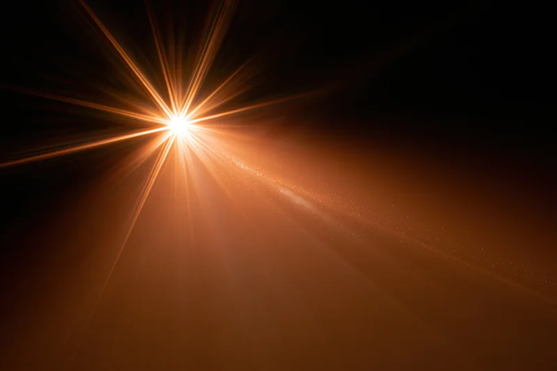 Intense light burst radiating from upper left corner with warm glow and particle trails across dark background