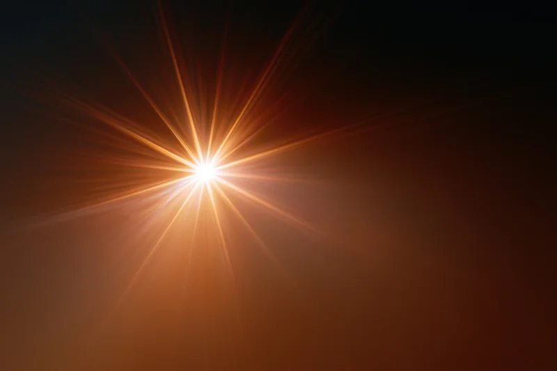 Intense light burst radiating from center against dark background with warm orange glow and copyspace