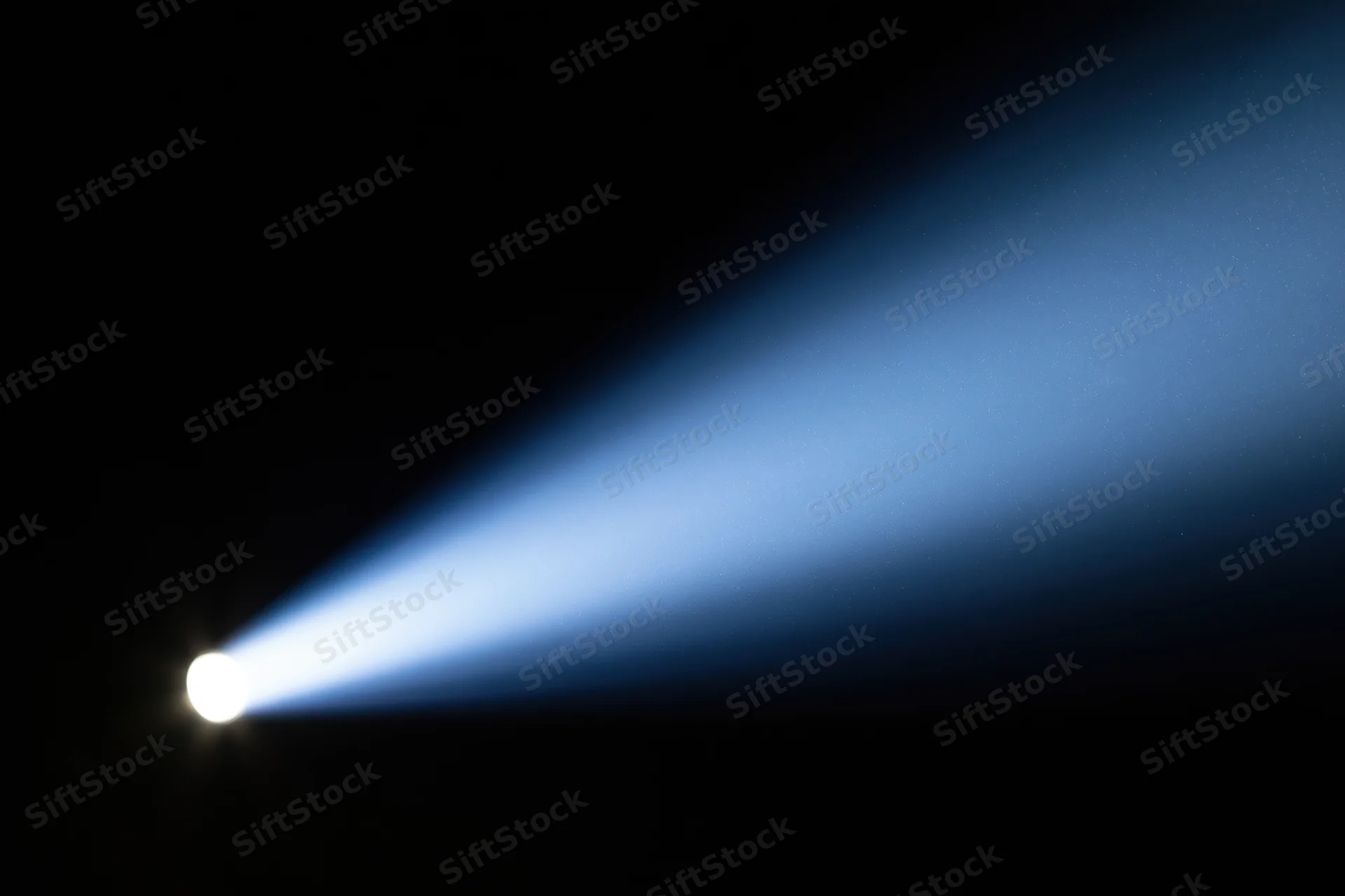 Intense spotlight beam cutting diagonally across dark background