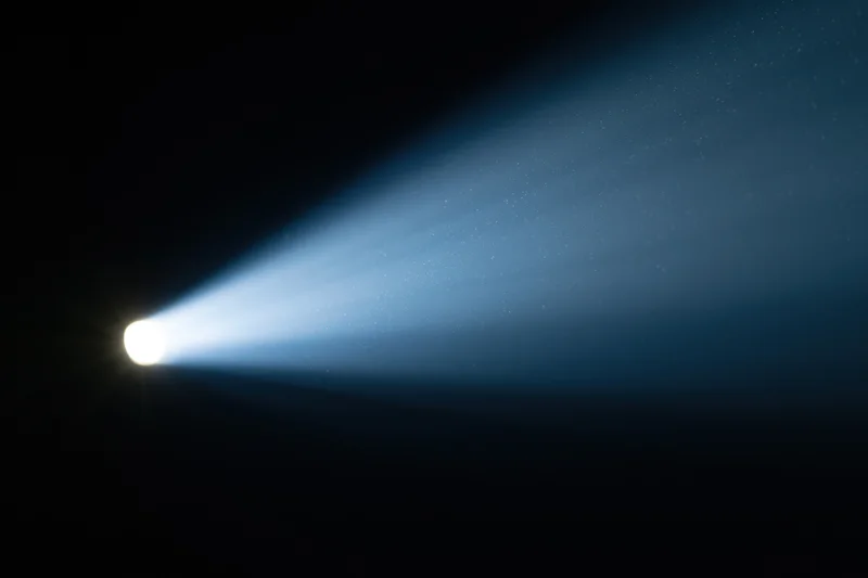 Intense spotlight beam cutting diagonally across dark space