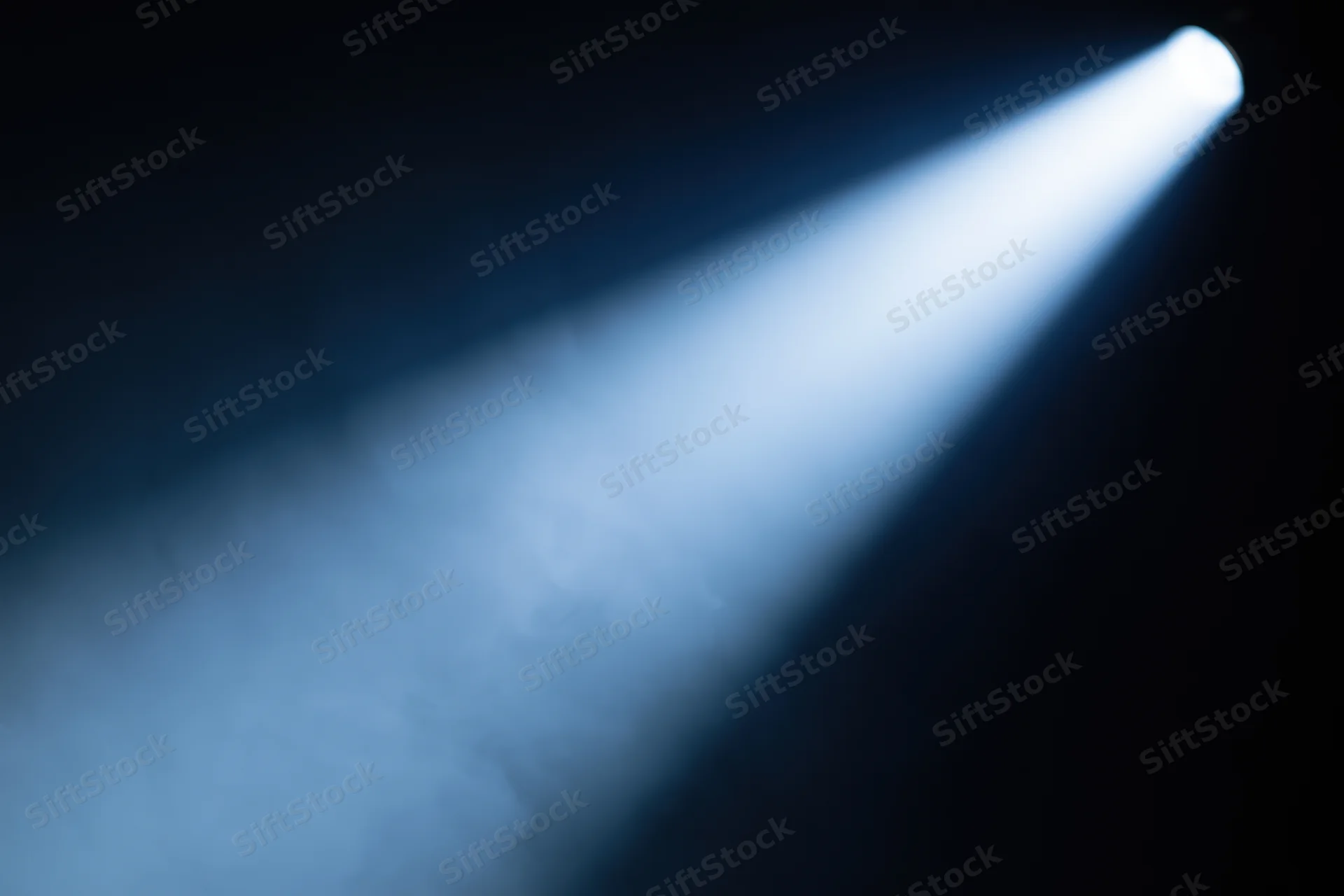 Single spotlight beam cutting diagonally through haze on stage