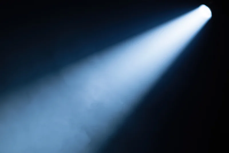 Single spotlight beam cutting diagonally through haze on stage