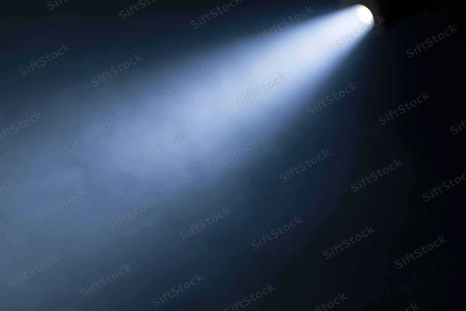 Single spotlight beam cutting diagonally through haze on stage