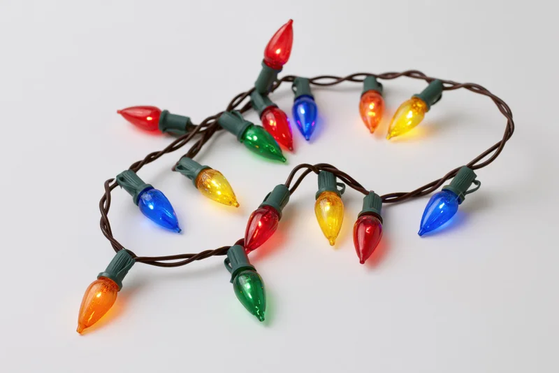 A single strand of multicolored christmas lights arranged in a loose loop on a white surface