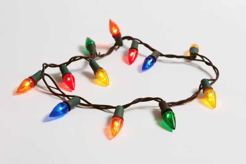 A single strand of multicolored christmas lights arranged in a loose loop on a white background