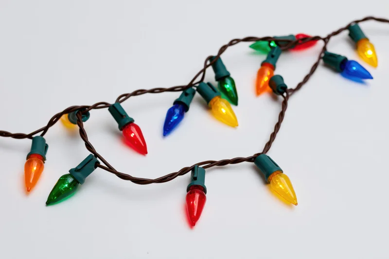 A single strand of multicolored christmas lights arranged on a white surface