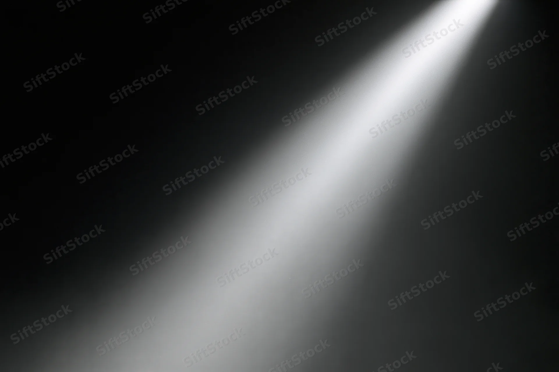 Single spotlight beam cutting diagonally through dark stage space