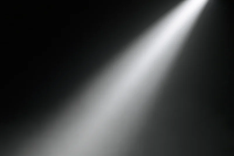 Single spotlight beam cutting diagonally through dark stage space