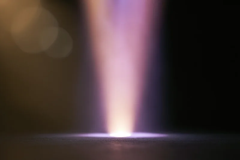 Vertical beam of light rising from a bright point on a dark surface