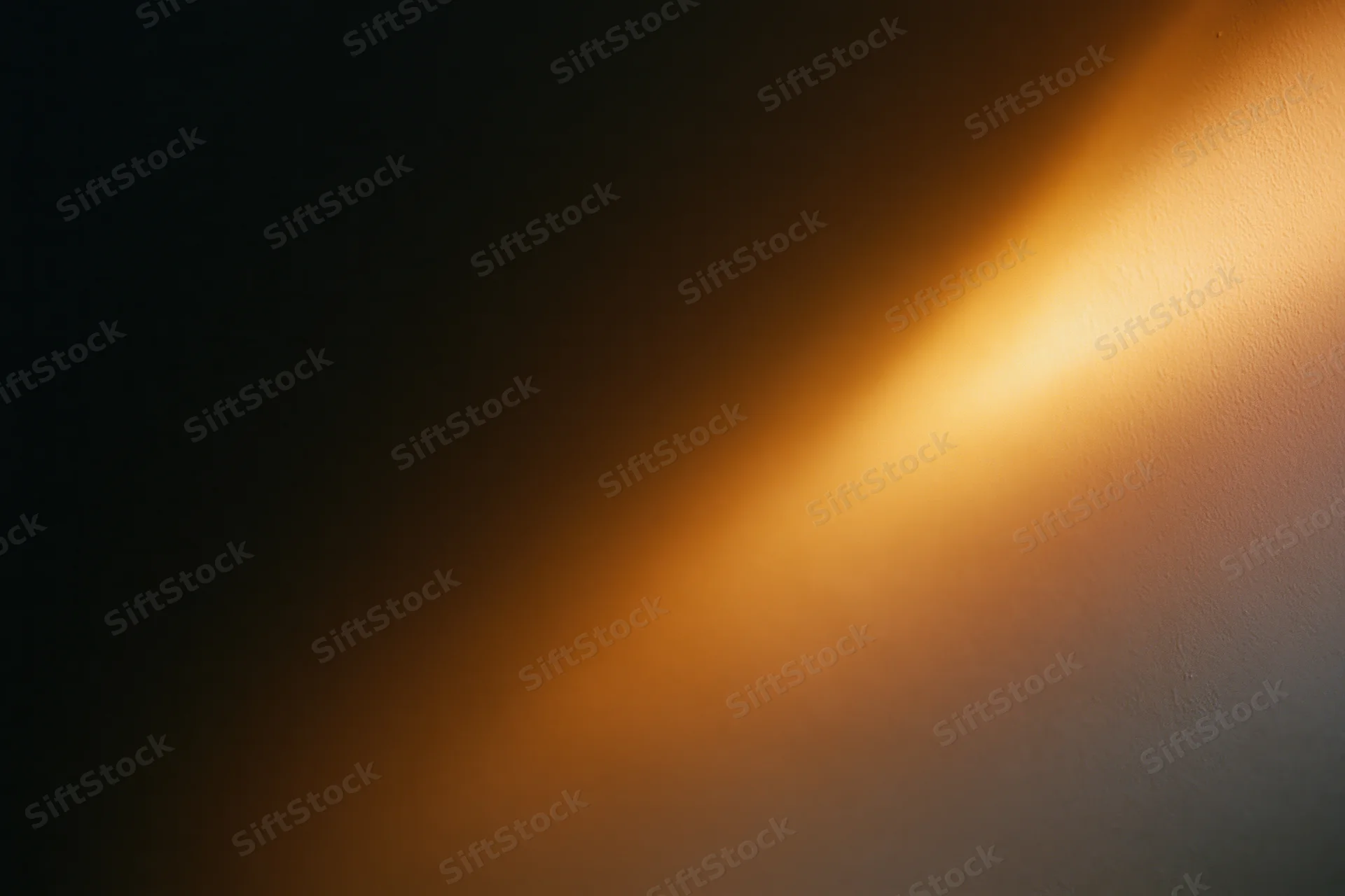 Warm amber light casting a soft diagonal glow across a textured wall interior