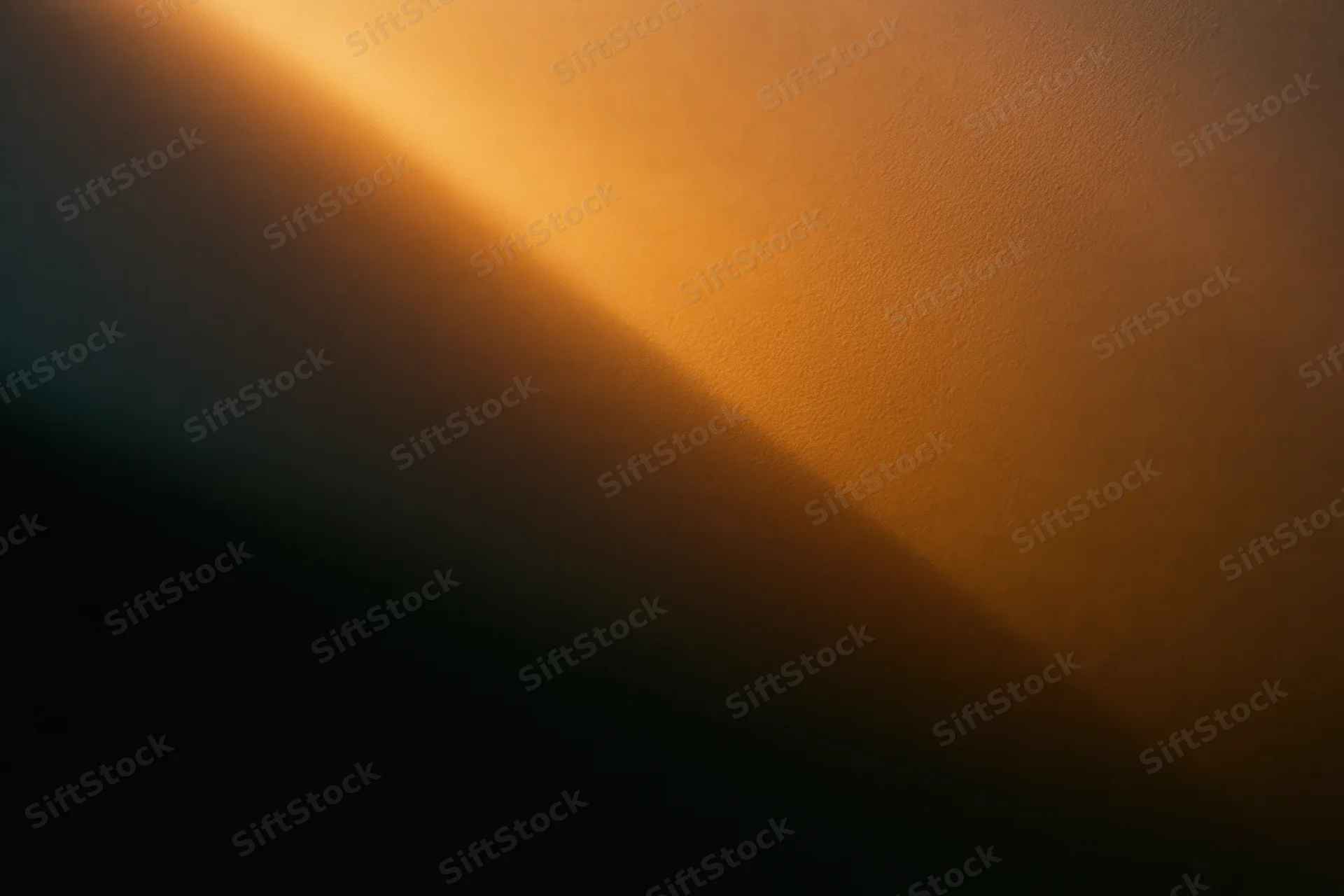 Warm amber light casting a soft diagonal glow across a textured wall surface