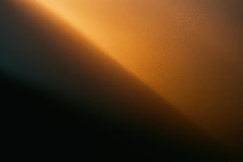 Warm amber light casting a soft diagonal glow across a textured wall surface