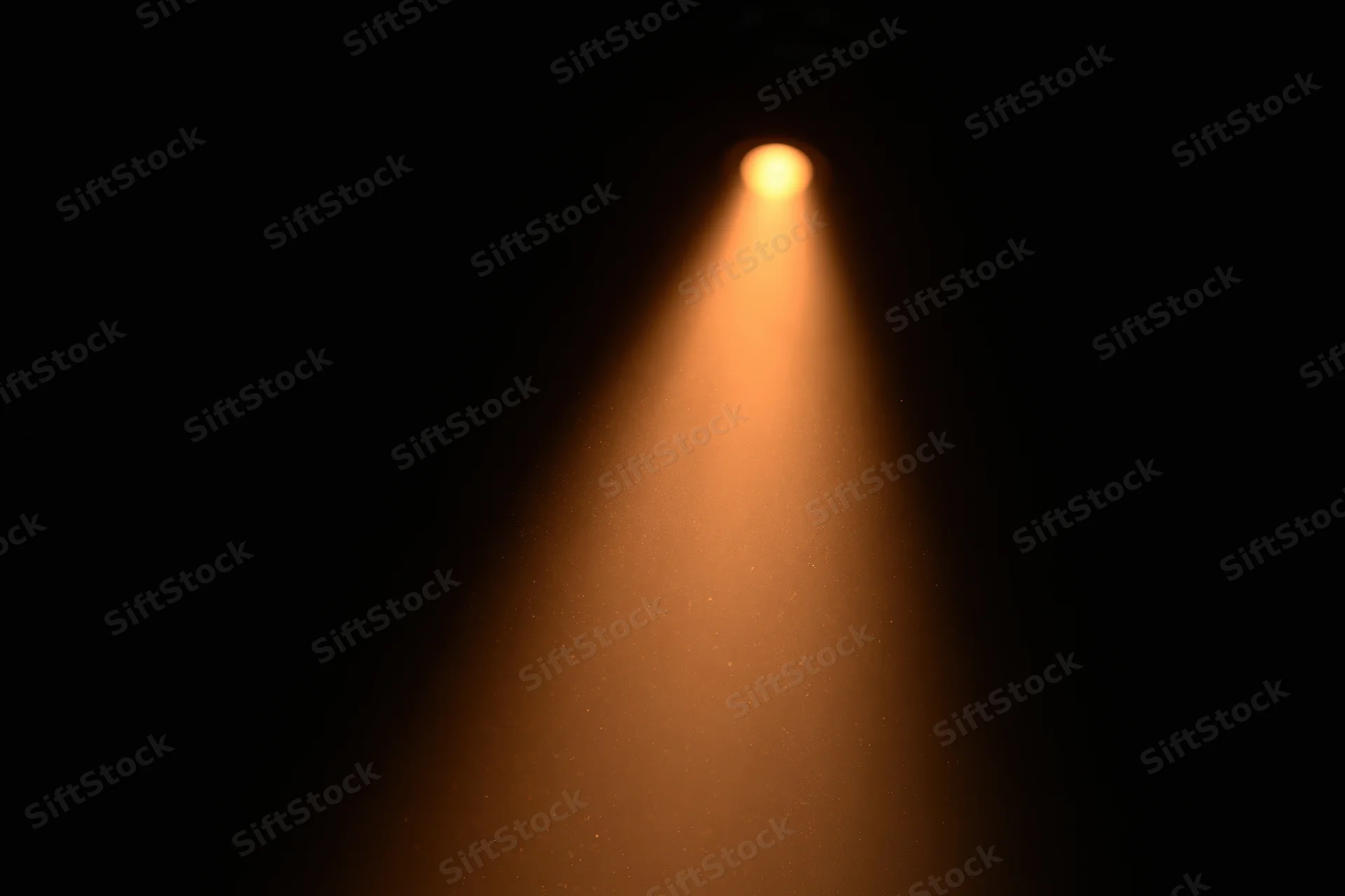 Warm amber spotlight beam cutting downward through dark space