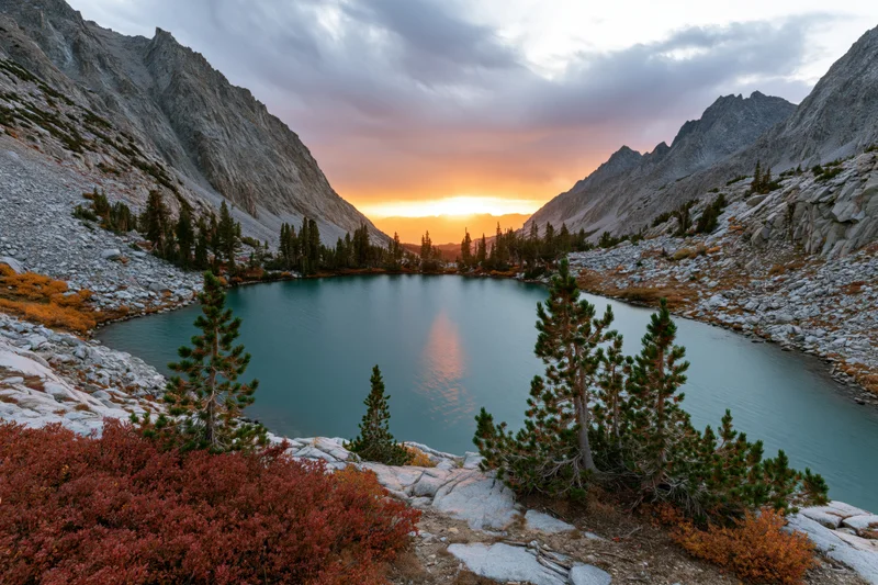 Turquoise alpine lake reflecting sunset in mountain valley surrounded by pine trees and autumn foliage