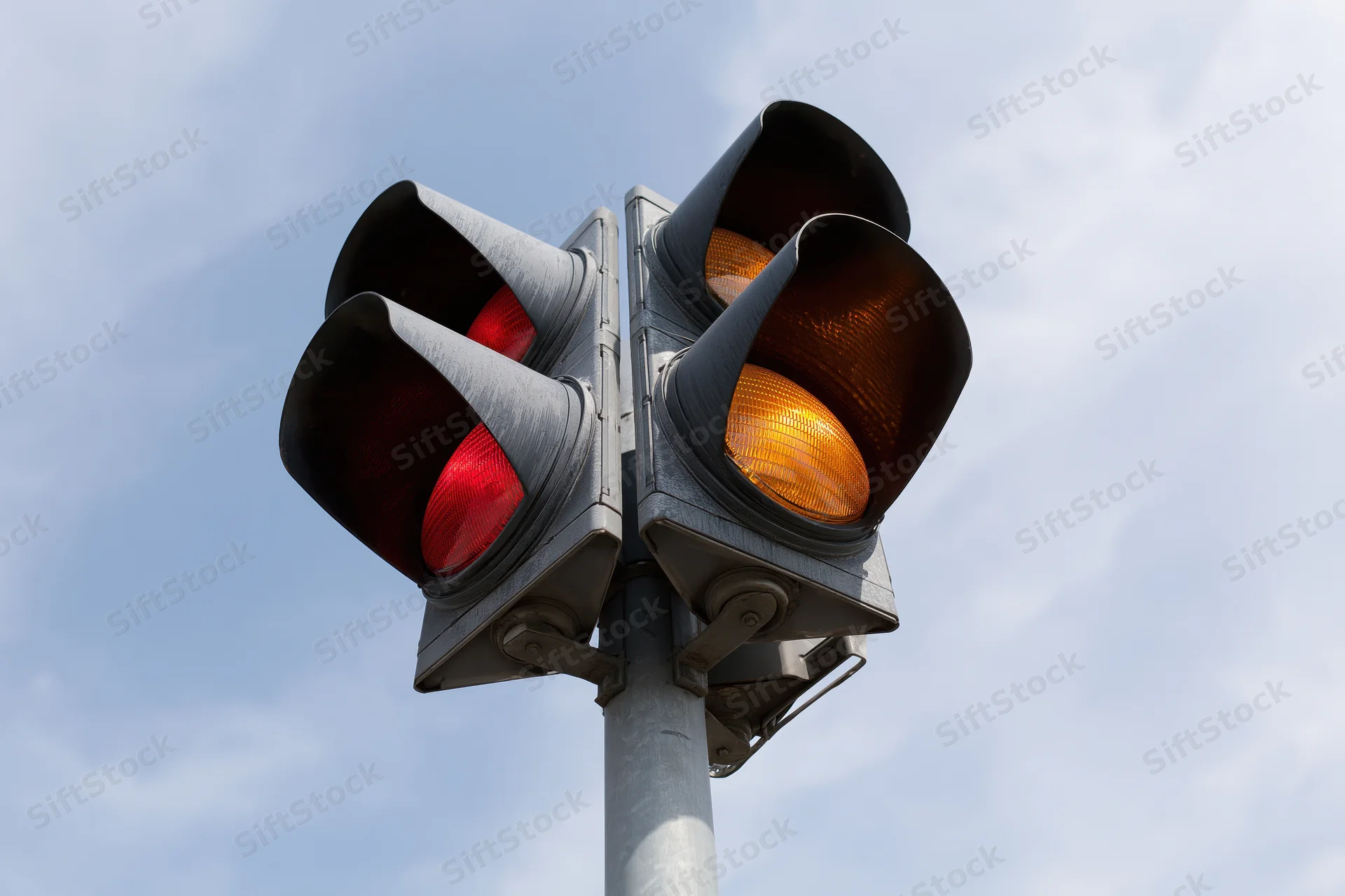 Traffic light showing red and amber illuminated simultaneously against sky
