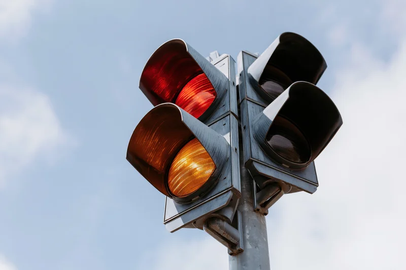 Traffic light with red and amber signals illuminated against a cloudy sky