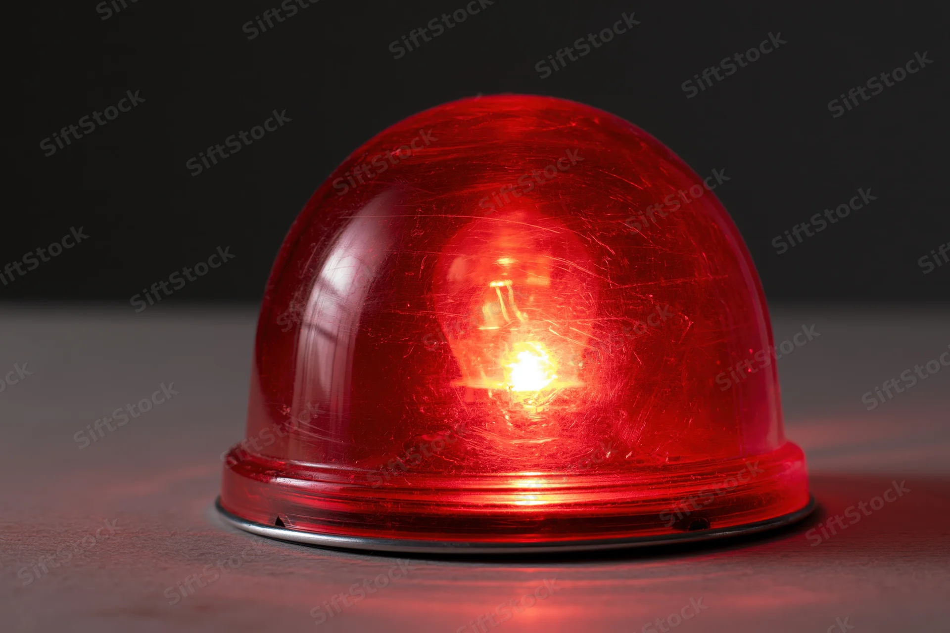 Vintage red emergency beacon light glowing intensely on a dark surface