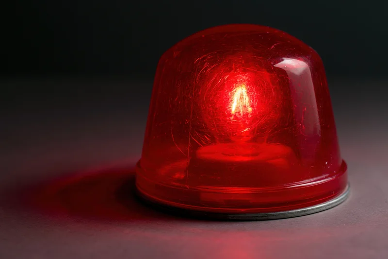 Vintage red emergency beacon light glowing intensely on dark surface