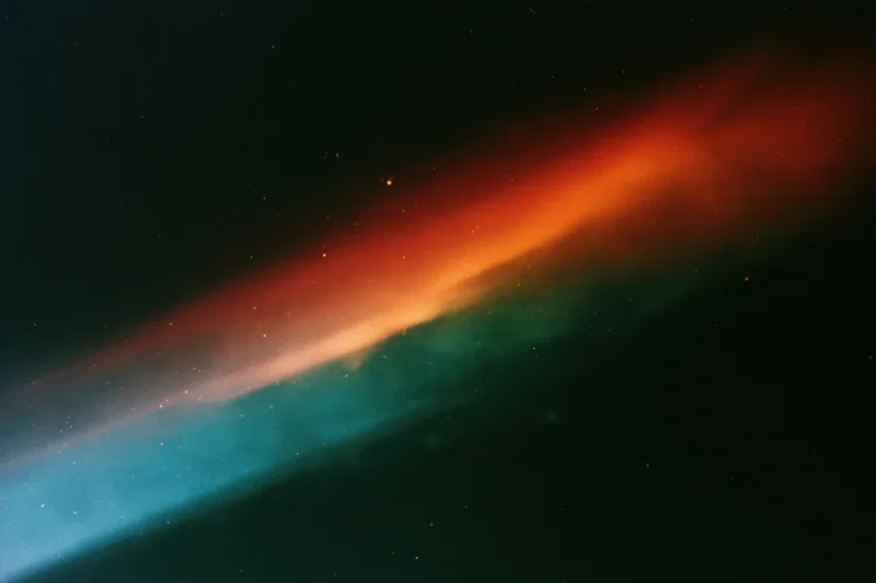 Diagonal light leak in red orange and blue across dark background