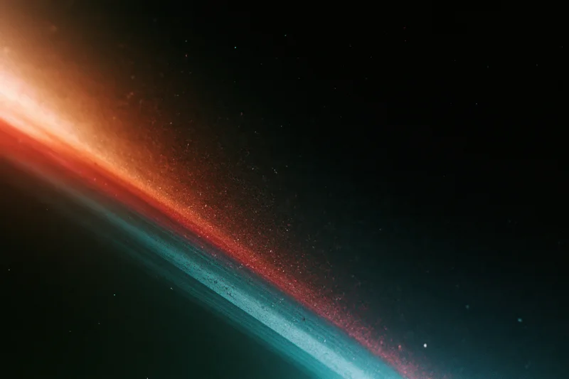Diagonal analog film light leak across dark background with red orange and teal gradient